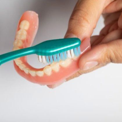 A toothbrush cleaning dentures